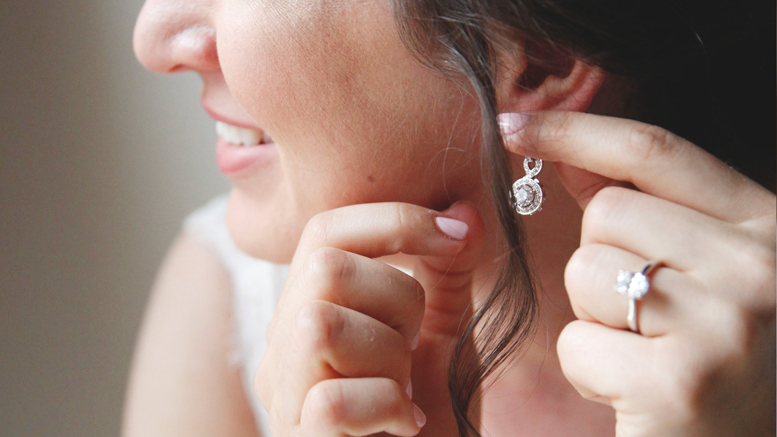 A bride putting on her Diamond Nexus drop earrings