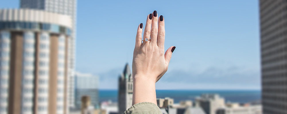 woman's hand with a ring on against a cityscape