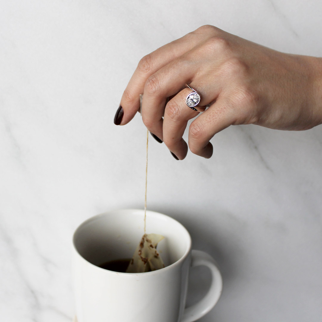 a bezel setting ring on a hand making tea