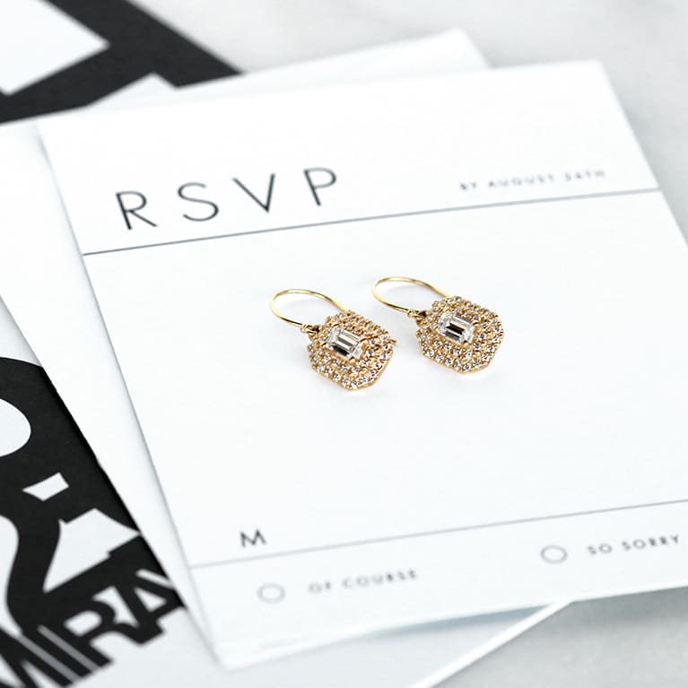 golden earrings on an RSVP card